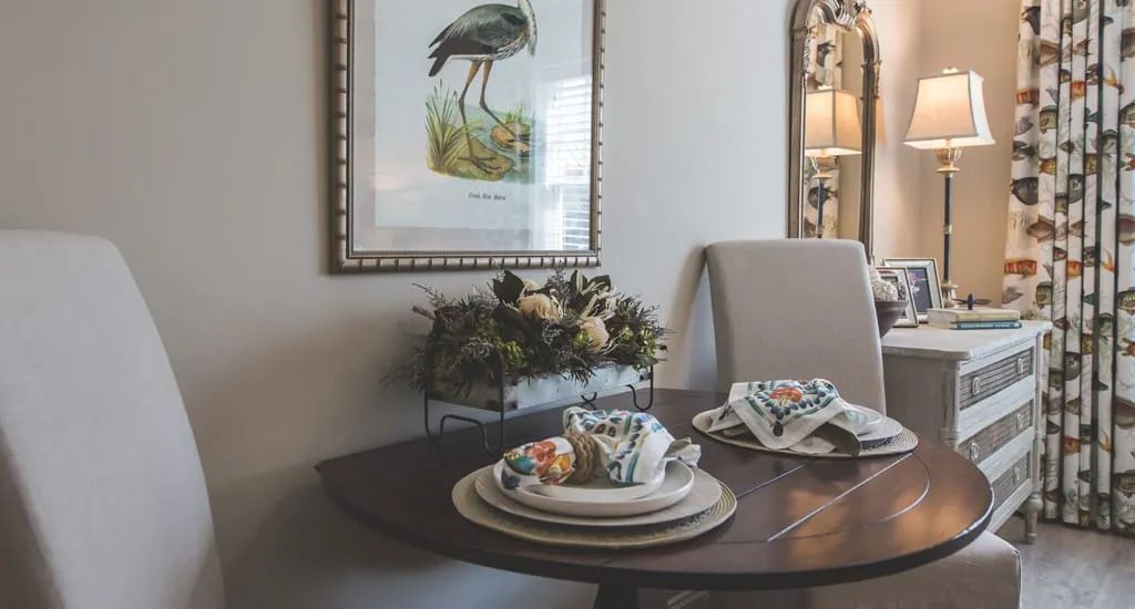 A cozy dining room setup with elegant tableware and wall art featuring a bird.