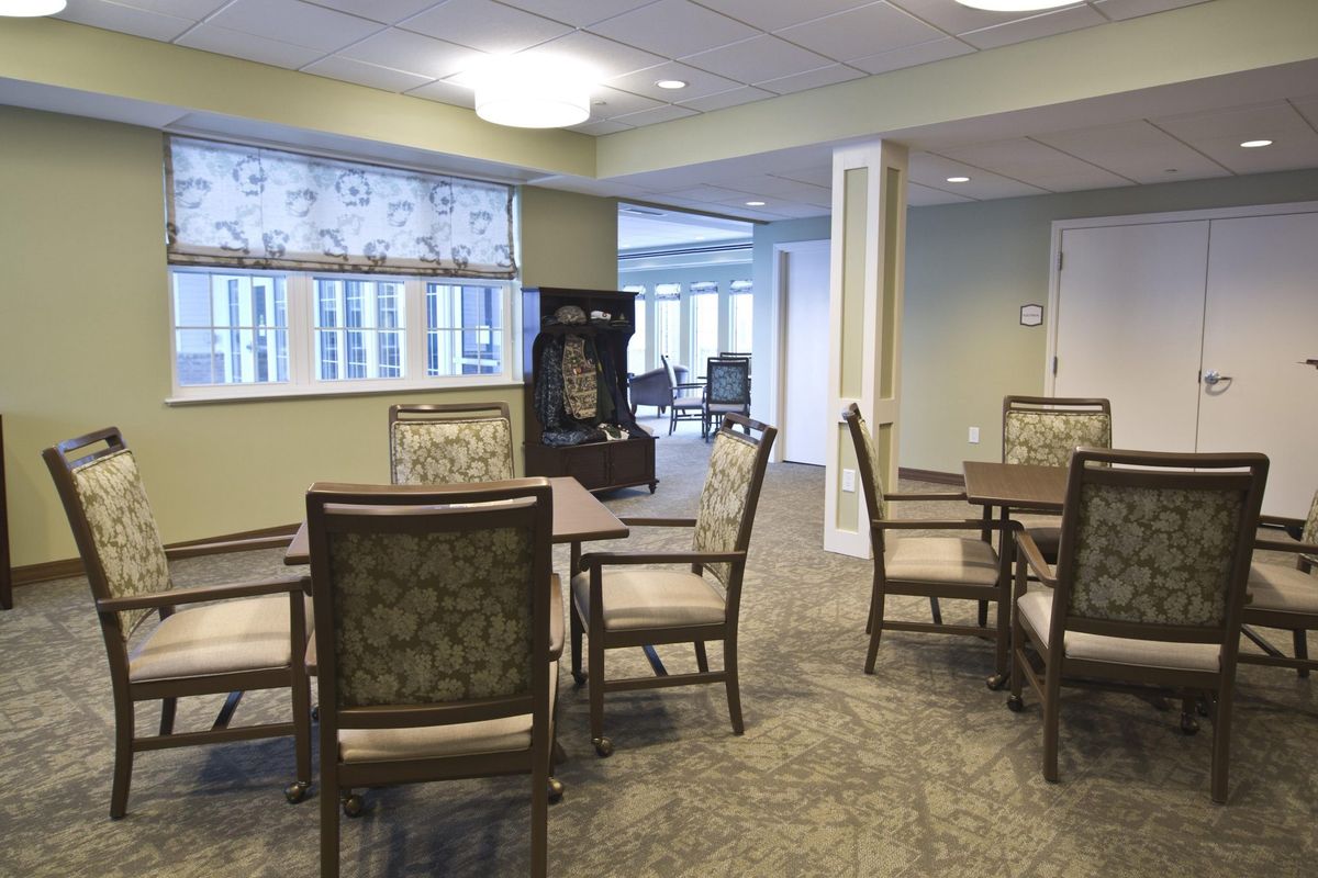 A cozy dining area with several tables and chairs, well-lit by overhead lighting and natural light from the windows.
