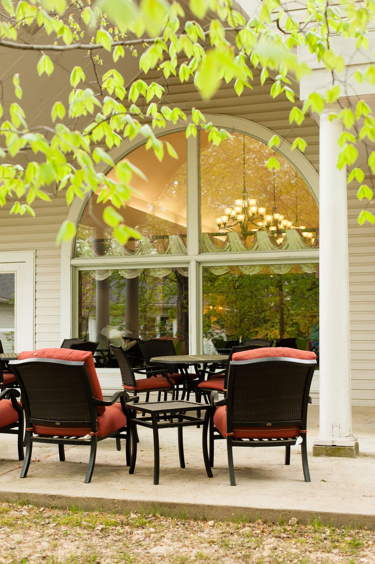 An inviting patio with comfortable seating and a view of large windows framed by greenery.