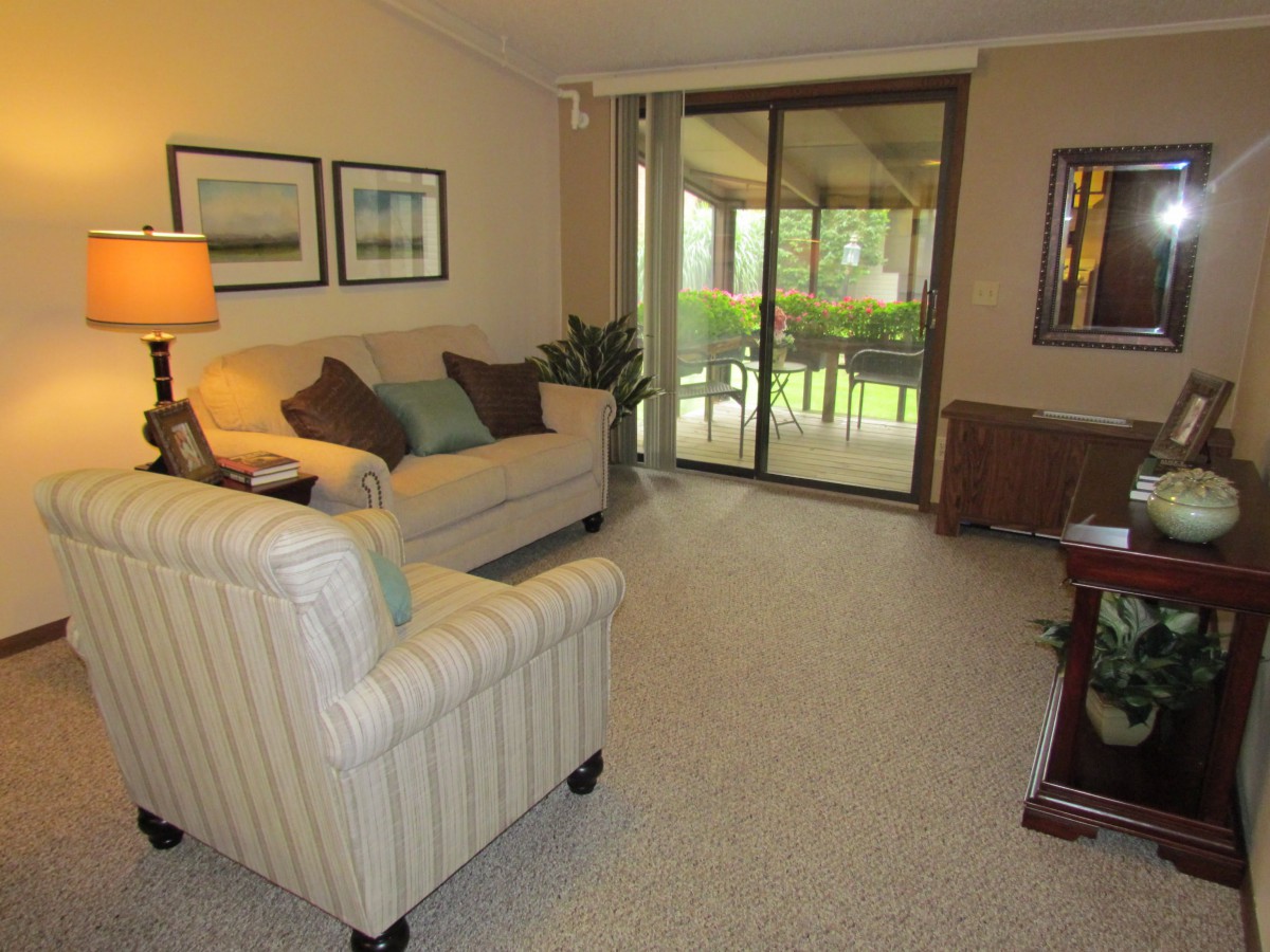 A cozy living room with comfortable seating and a view of the outdoors through sliding glass doors.