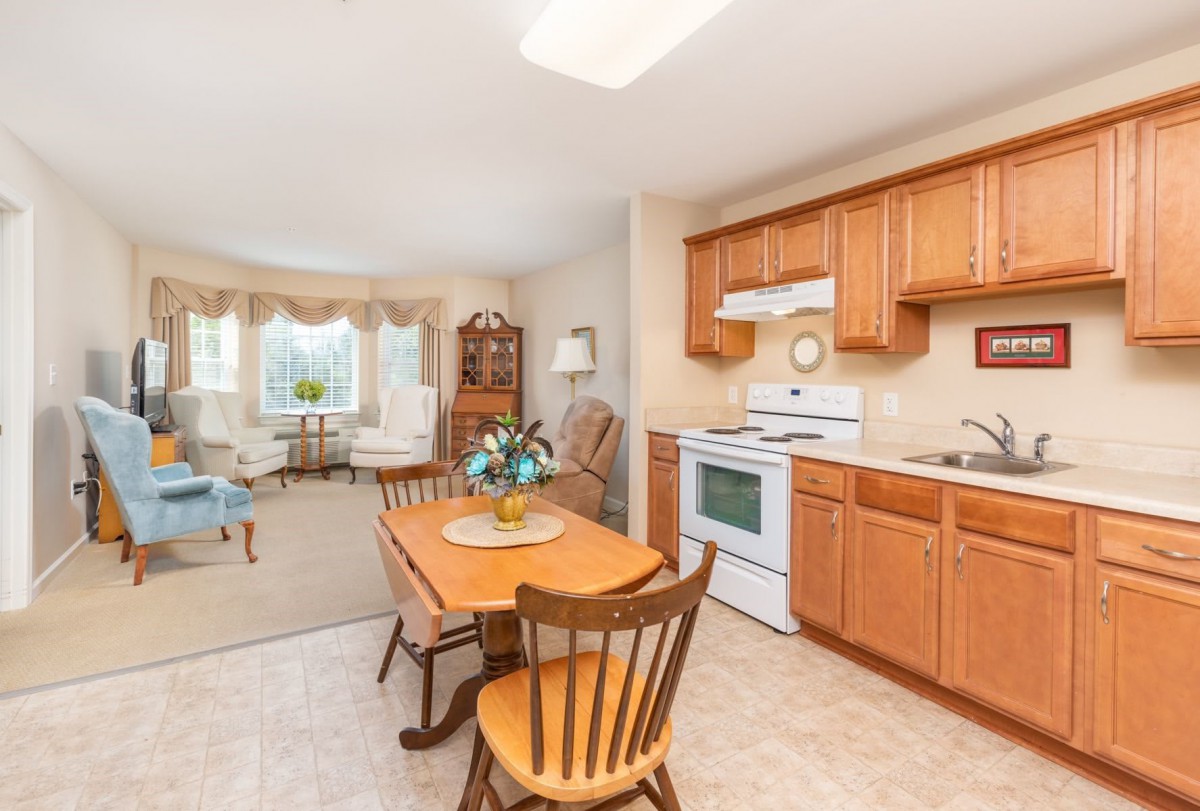 A cozy kitchen and dining area connected to a living room with wooden furniture and cabinetry.