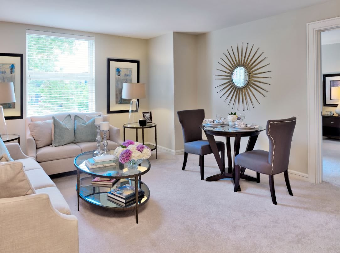 A cozy living room with modern decor, featuring a sofa, coffee table, and a small dining area.