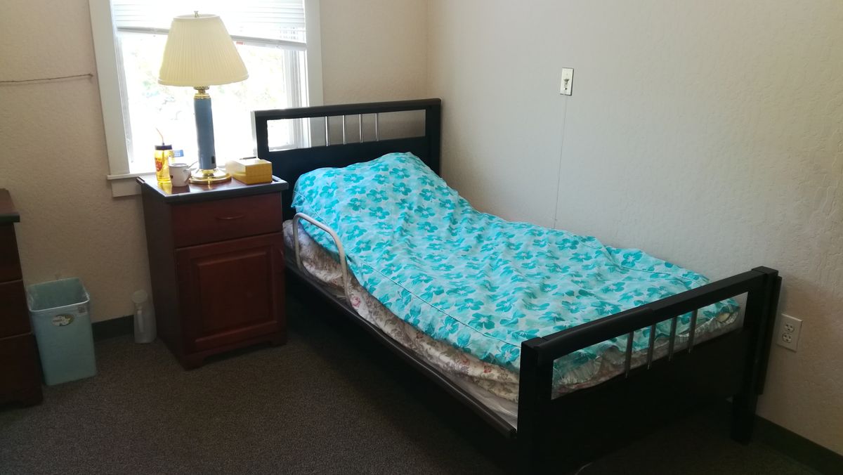 A cozy bedroom with a single bed, nightstand, and lamp.