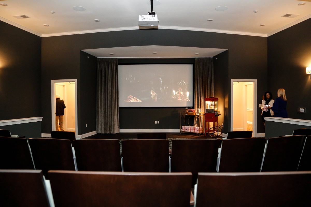 Empty theater room with a projector screen and rows of seats.
