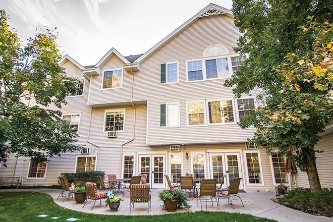 A view of a residential building with a spacious patio area, surrounded by trees.