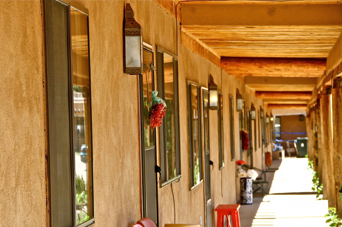 A long outdoor corridor of a motel with rustic architecture.