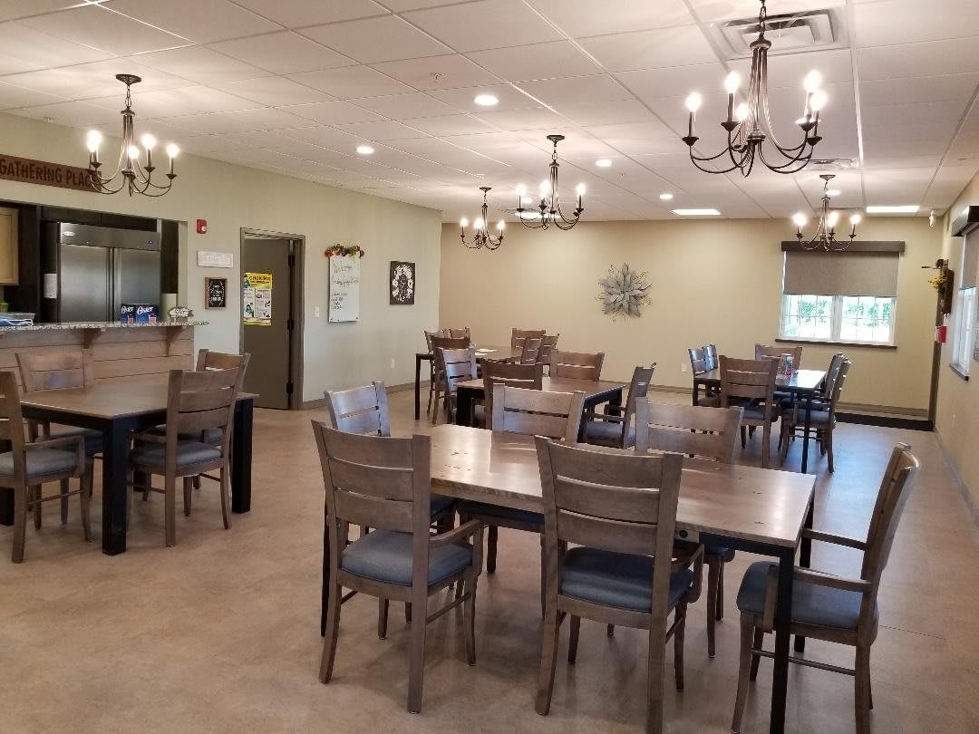 A spacious dining room featuring wooden tables and chairs, illuminated by elegant chandeliers.