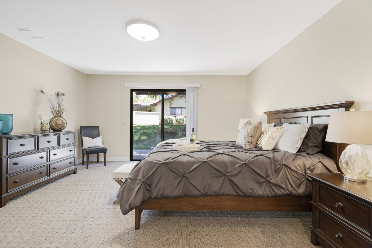 A well-lit bedroom featuring a large bed, contemporary decor, and access to an outdoor area through a sliding glass door.