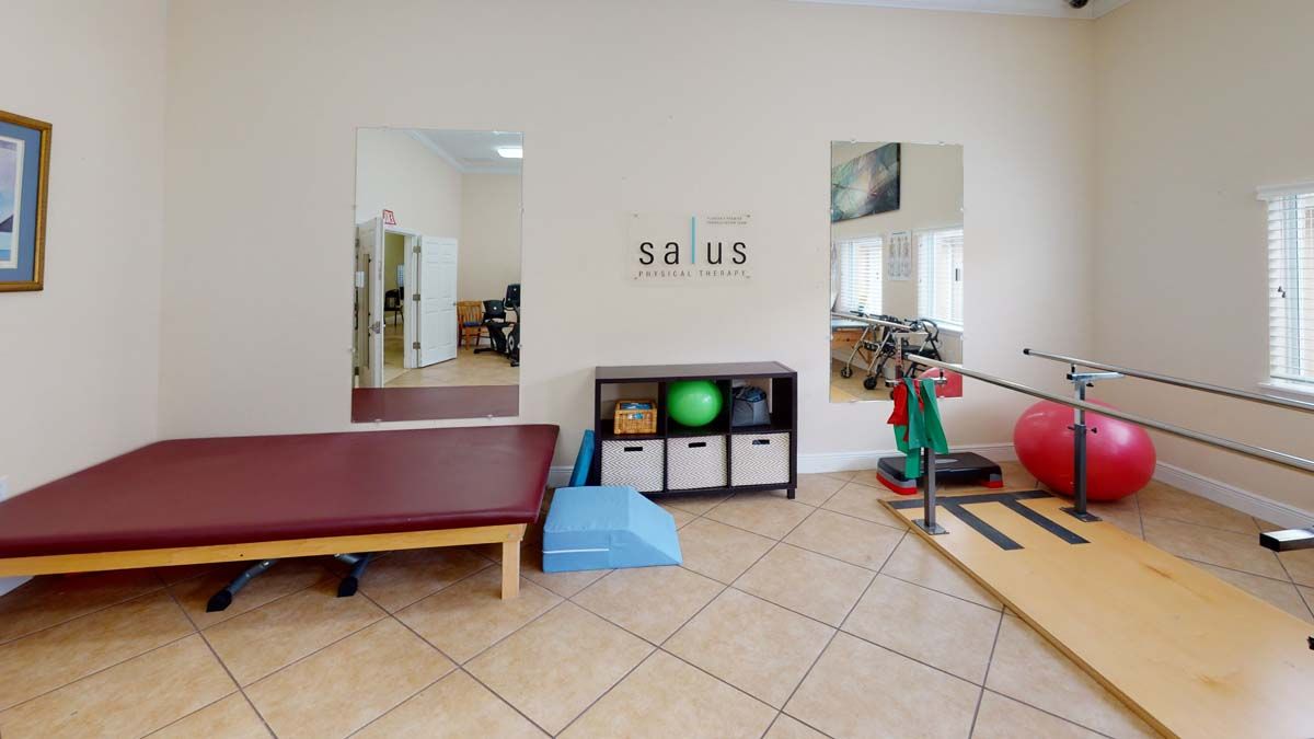 A physical therapy room equipped with mirrors, a massage table, balance training tools, and various rehabilitation equipment.