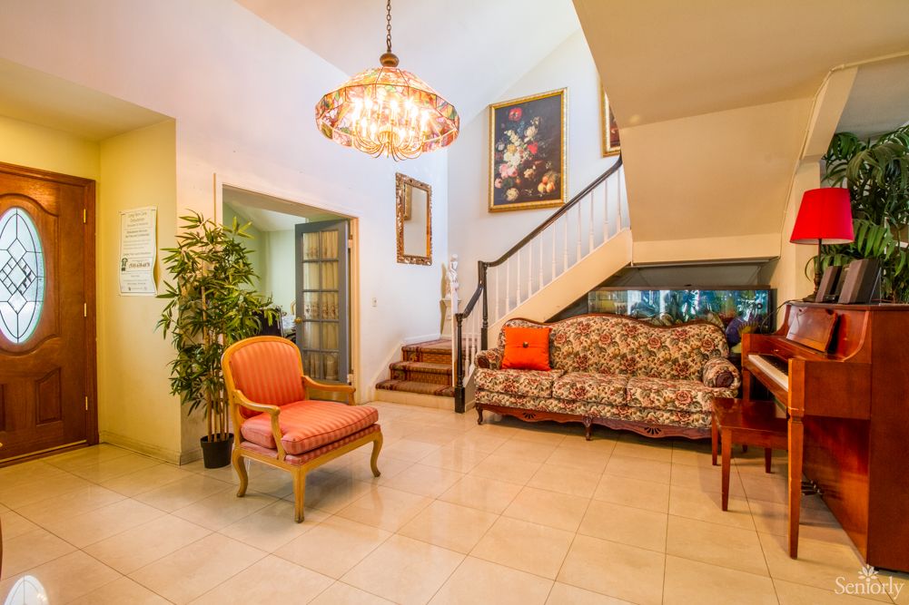 A cozy living room with elegant furniture, a chandelier, and decorative wall art.