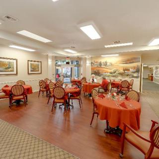 A cozy dining area with tables and chairs arranged neatly, featuring warm lighting and elegant decor.