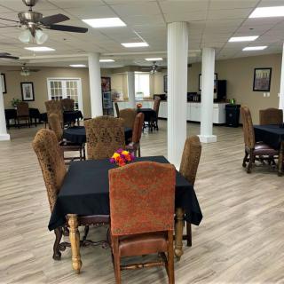 A spacious dining area with multiple tables and chairs, ceiling fans, and a hardwood floor.