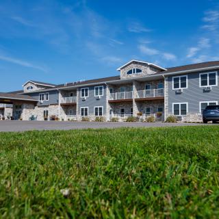 A modern residential building with a well-maintained lawn and clear blue skies.