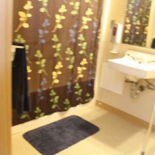 A bathroom with a floral patterned shower curtain, sink, and a dark mat.