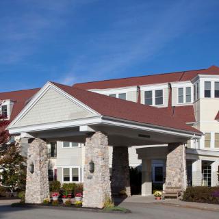 A residential building with a prominent entrance featuring stone pillars and a red roof.