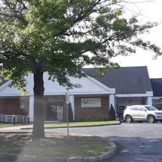 A view of a commercial building surrounded by greenery and parked vehicles.