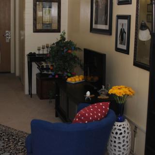 A cozy living room with blue furniture, decorative artwork, and vibrant flowers.