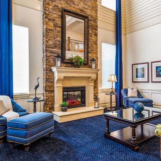 A modern living room with a stone fireplace, blue furnishings, and large windows.