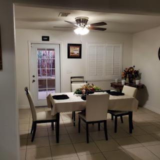 A cozy dining area featuring a table set for meals, surrounded by comfortable chairs and decorated with plants.