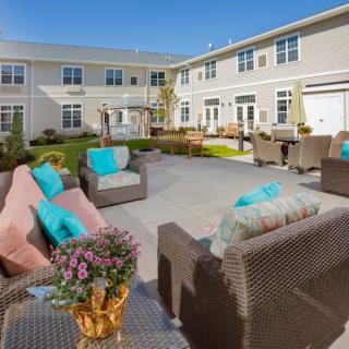 A cozy outdoor courtyard featuring wicker furniture with colorful cushions in a residential setting.