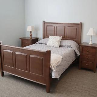 A neatly arranged bedroom featuring a wooden bed with matching nightstands and lamps.