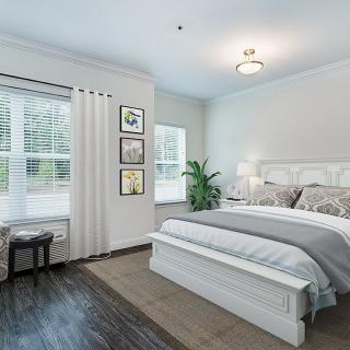 A modern bedroom with stylish decor, featuring a large bed, a plant, and natural light from the windows.