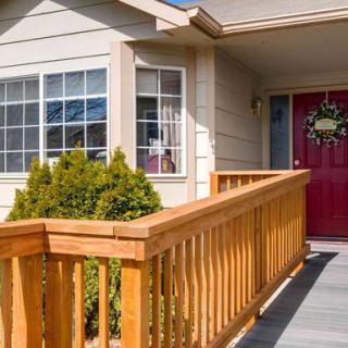A house entrance with a wooden ramp and red front door.