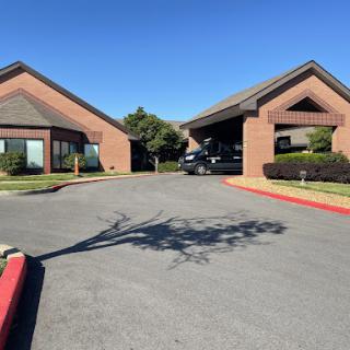 A view of two adjacent buildings with a clear blue sky overhead and a well-maintained parking area.