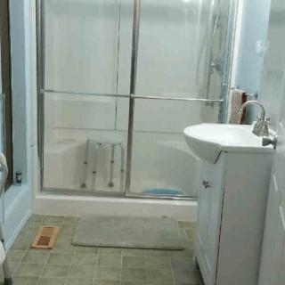 A modern bathroom featuring a shower with sliding doors, a sink with a mirror above it, and a tiled floor.