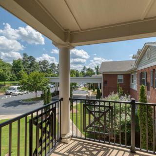 A view from a balcony overlooking an apartment complex, with clear skies and lush greenery.