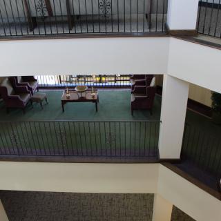 An interior view of a multi-story lobby with a seating area and balconies overlooking the atrium.