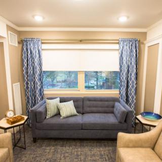 A cozy living room with a blue sofa, patterned curtains, and comfortable chairs.