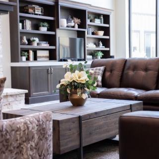 A cozy living room with a large sofa, coffee table, and decorative bookshelves.