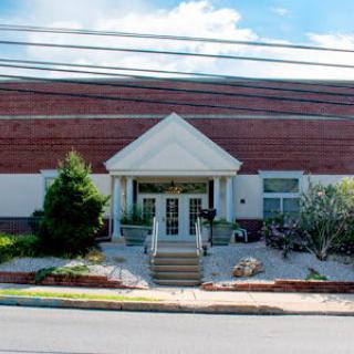 Entrance of a brick commercial building with landscaped surroundings.