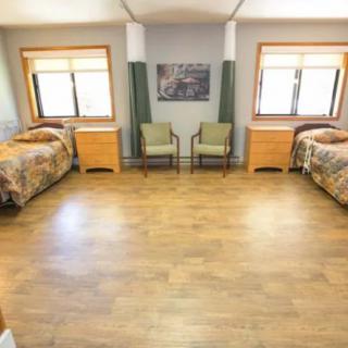 A spacious bedroom with two single beds, wooden flooring, and large windows.
