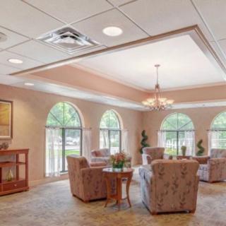 A cozy seating area with upholstered chairs and a chandelier, featuring large arched windows that let in natural light.