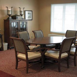 A dining room with a wooden table and chairs, featuring a window and cabinet.