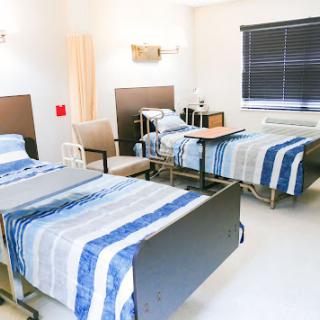 A well-equipped hospital patient room featuring two adjustable beds and essential furniture.