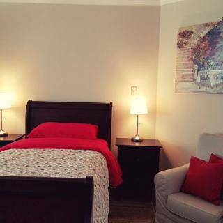 A cozy bedroom with a neatly made bed, nightstands, and warm lighting.