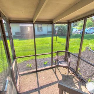 A sunny, screened-in porch overlooking a lush green yard.