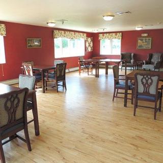 A spacious dining room with elegant chairs and tables, featuring hardwood floors and large windows.
