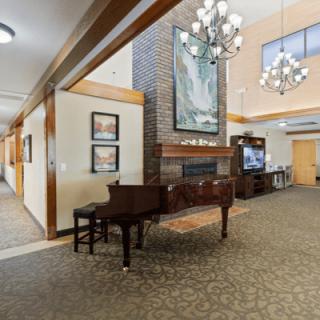 A beautifully decorated lobby featuring a grand piano, chandelier, and fireplace.