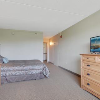 A minimalist bedroom with a bed, dresser, and TV.