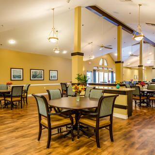 A cozy dining area with tables, chairs, and warm lighting.