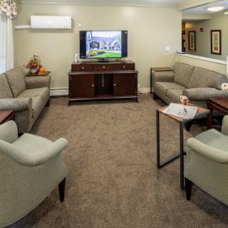 A cozy living room with multiple sofas, a television, and a coffee table on a carpeted floor.
