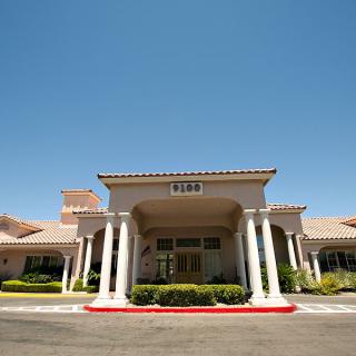 The front entrance of a building featuring pillars and a clear blue sky.