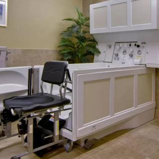 An accessible bathroom with a specialized bathtub and wheelchair for medical use.