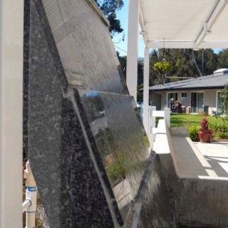 A memorial stone slab with engraved inscriptions, set in an outdoor garden on a sunny day.
