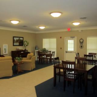 A cozy living room area with tables, chairs, and sofas arranged for relaxation.