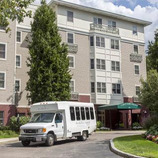 A shuttle bus parked in front of a hotel building.